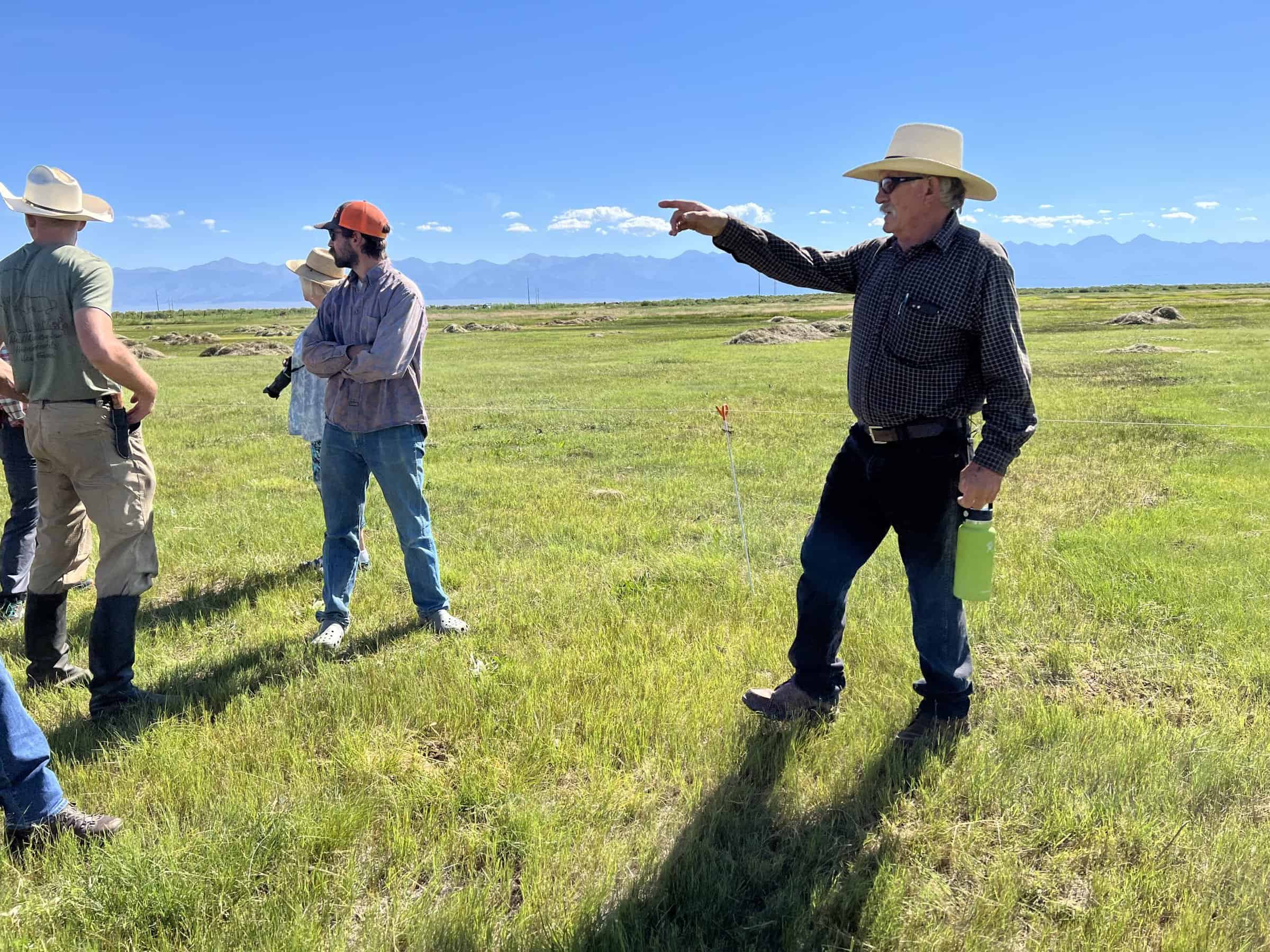Rancher George Whitten points out in his green field to tour attendees